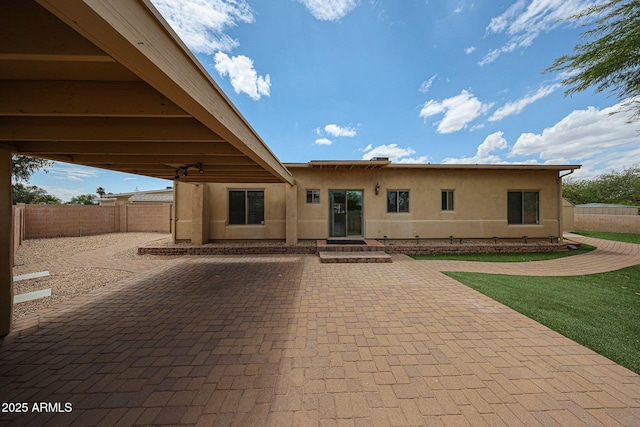 back of property with stucco siding, a patio area, and a fenced backyard