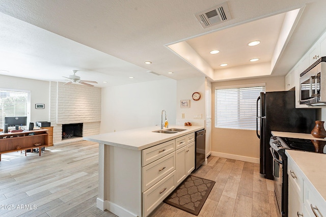 kitchen with visible vents, white cabinets, a sink, light wood-type flooring, and black appliances