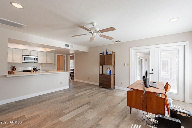 kitchen featuring light wood-style floors, visible vents, stainless steel microwave, and light countertops