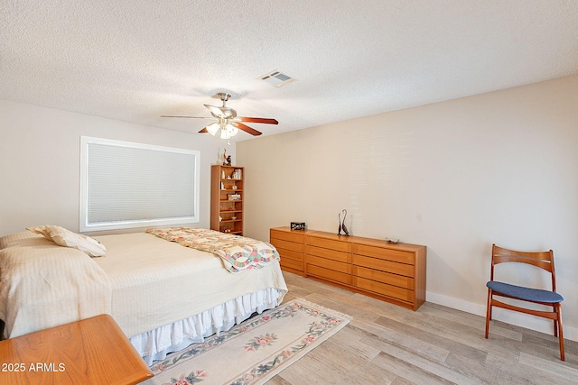 bedroom with a textured ceiling, visible vents, baseboards, a ceiling fan, and light wood-type flooring