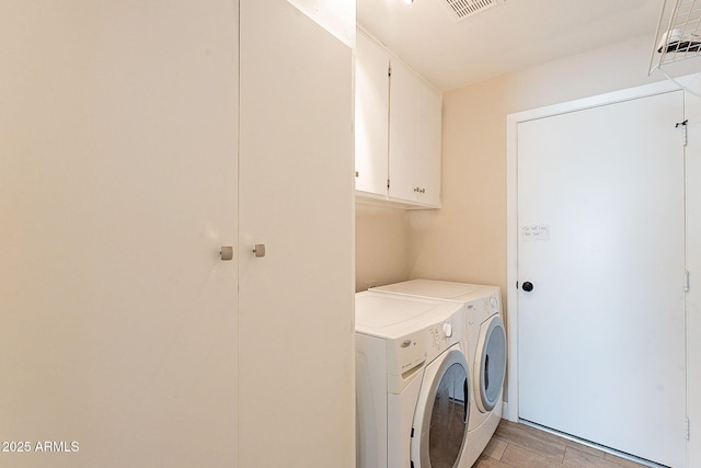 laundry area with cabinet space, light wood-style flooring, visible vents, and washer and clothes dryer