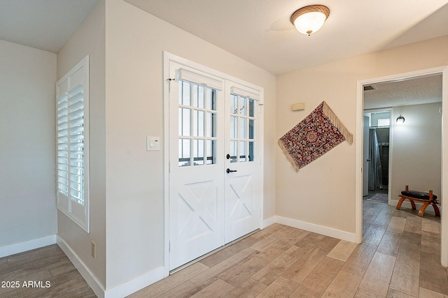 foyer entrance with light wood-style floors, plenty of natural light, and baseboards