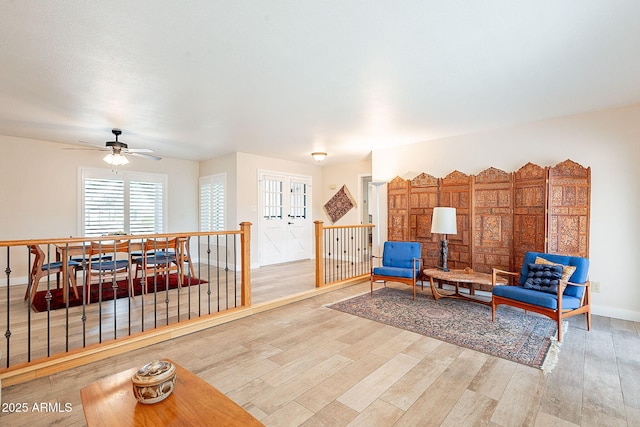 living area featuring baseboards, wood finished floors, and an upstairs landing