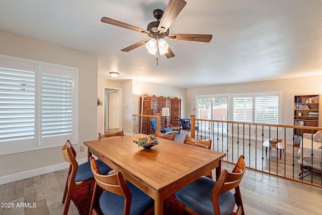 dining area featuring ceiling fan, light wood-style flooring, and baseboards