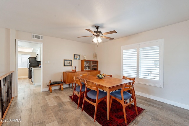 dining area with light wood-type flooring, baseboards, visible vents, and a ceiling fan