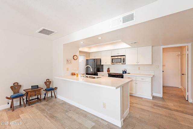 kitchen featuring black appliances, white cabinetry, visible vents, and light wood-style floors