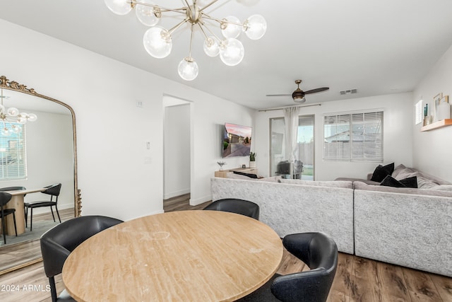 dining space with ceiling fan with notable chandelier, wood finished floors, visible vents, and baseboards