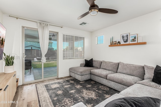 living room with a ceiling fan, visible vents, and light wood-type flooring