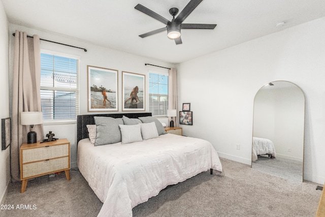 bedroom featuring baseboards, arched walkways, carpet floors, and ceiling fan