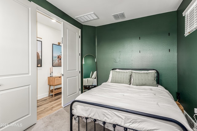 bedroom with light wood-type flooring, visible vents, and baseboards