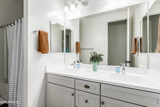 full bath with double vanity, a shower with curtain, and a sink