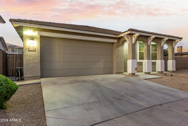 ranch-style house featuring fence, a tile roof, stucco siding, driveway, and an attached garage