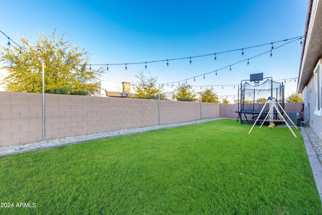 view of yard with a trampoline, a fenced backyard, and cooling unit