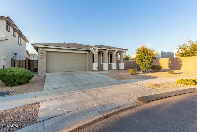 view of front of house with stucco siding, an attached garage, driveway, and fence