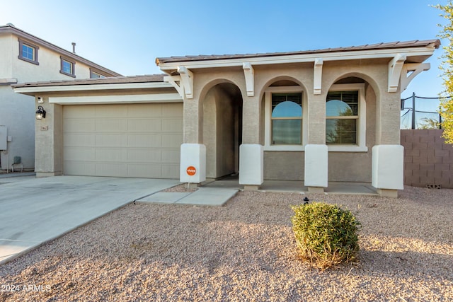 view of front facade with a porch, stucco siding, an attached garage, and driveway