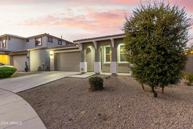 view of front of house featuring a tile roof, concrete driveway, a garage, and stucco siding