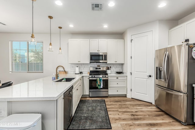 kitchen with visible vents, a peninsula, a sink, decorative backsplash, and stainless steel appliances