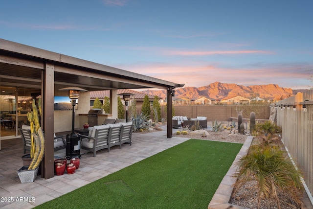 yard at dusk with an outdoor living space, a patio, a mountain view, and exterior kitchen