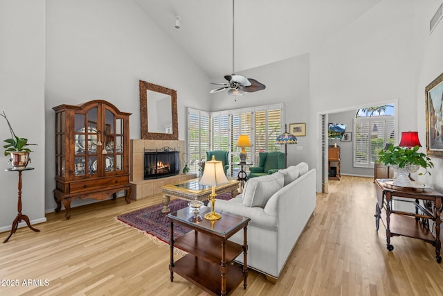 10429 N 101st St, Scottsdale, AZ 85258 - living room with high vaulted ceiling, a tile fireplace, light wood finished floors, a ceiling fan, and baseboards