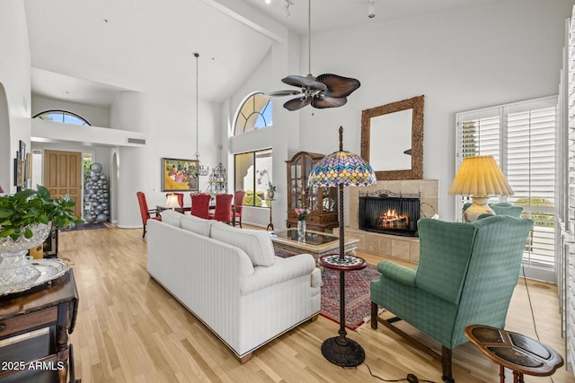 10429 N 101st St, Scottsdale, AZ 85258 - living room with high vaulted ceiling, a tile fireplace, a ceiling fan, beam ceiling, and light wood-style floors