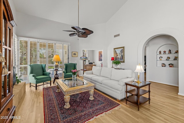10429 N 101st St, Scottsdale, AZ 85258 - living room with ceiling fan, a high ceiling, light wood-style flooring, arched walkways, and baseboards