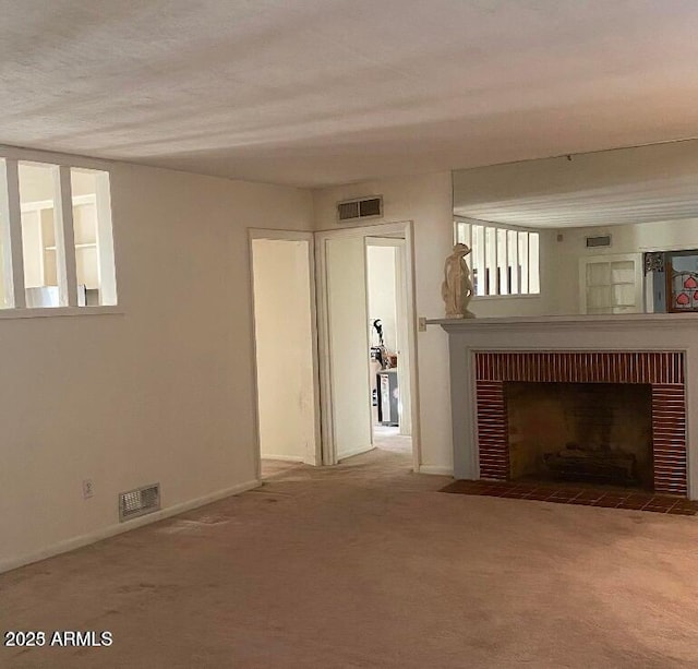 unfurnished living room with visible vents, carpet, and a fireplace with flush hearth