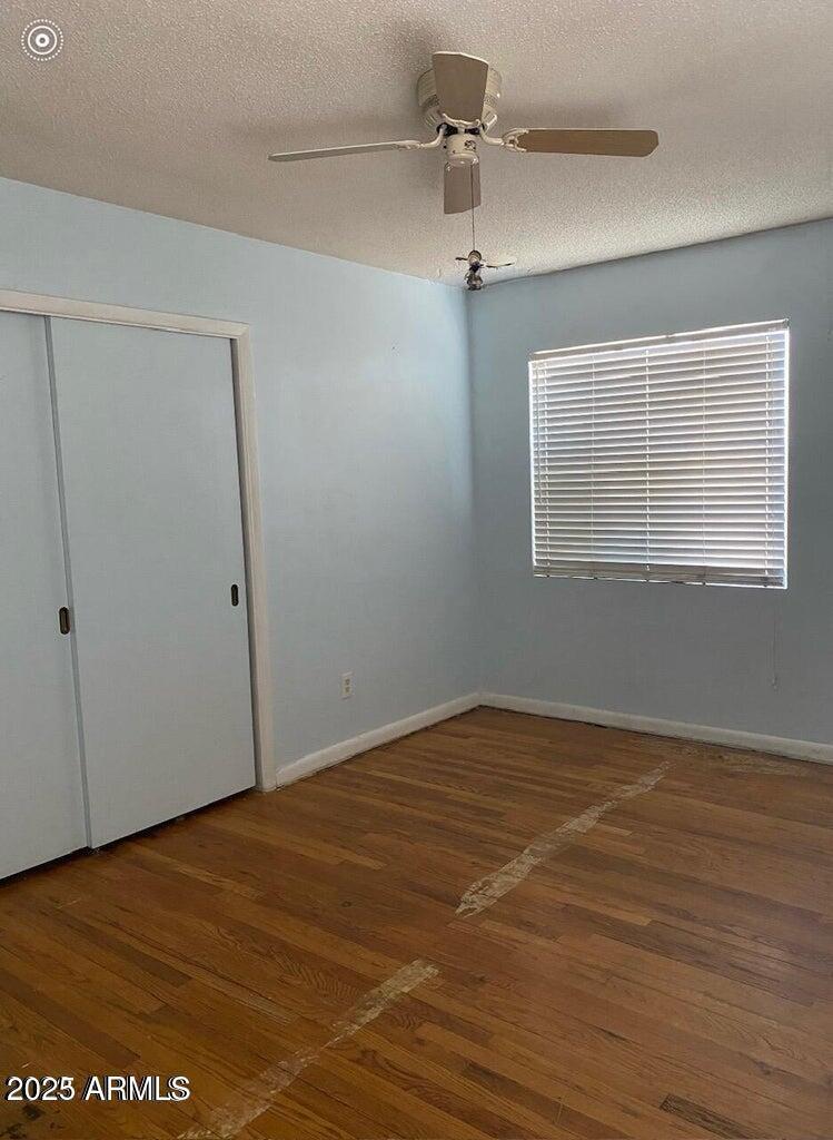 unfurnished bedroom with a closet, baseboards, wood finished floors, and a textured ceiling