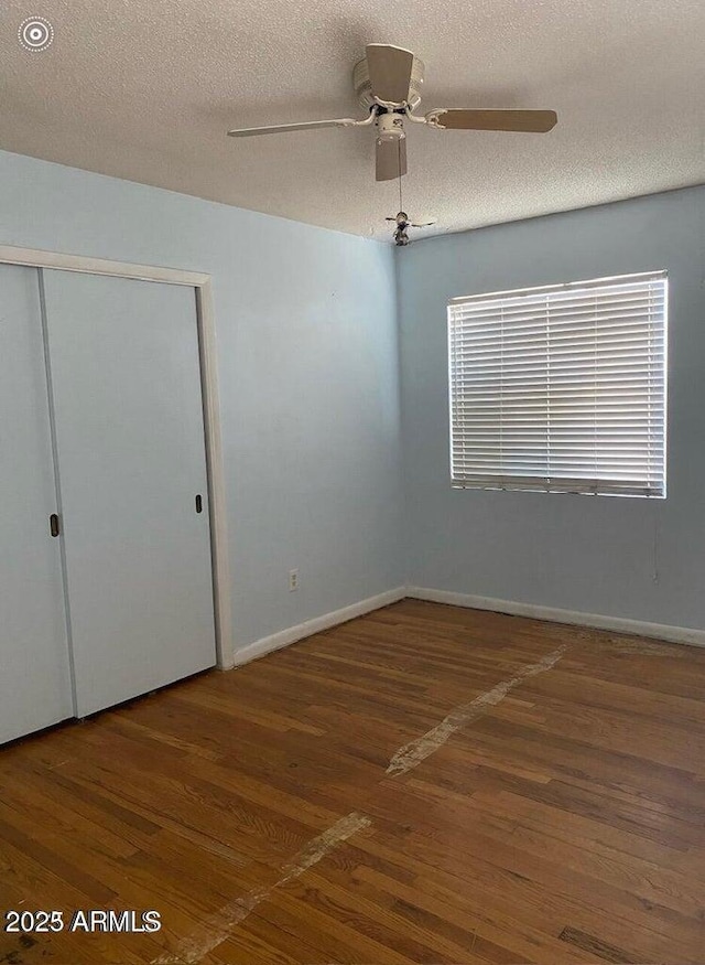 unfurnished bedroom with a closet, baseboards, wood finished floors, and a textured ceiling