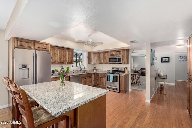 kitchen with visible vents, light wood finished floors, ceiling fan, a sink, and appliances with stainless steel finishes