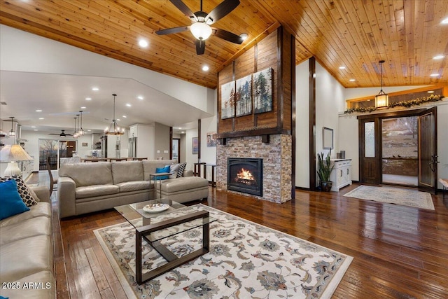 living room with a stone fireplace, high vaulted ceiling, dark hardwood / wood-style flooring, ceiling fan, and wood ceiling