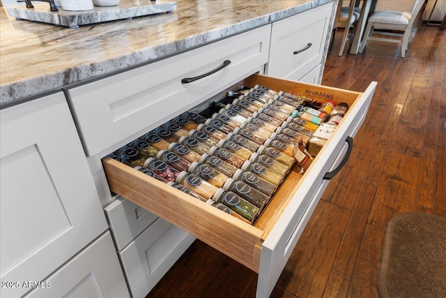 interior details with light stone counters, dark hardwood / wood-style floors, and white cabinets