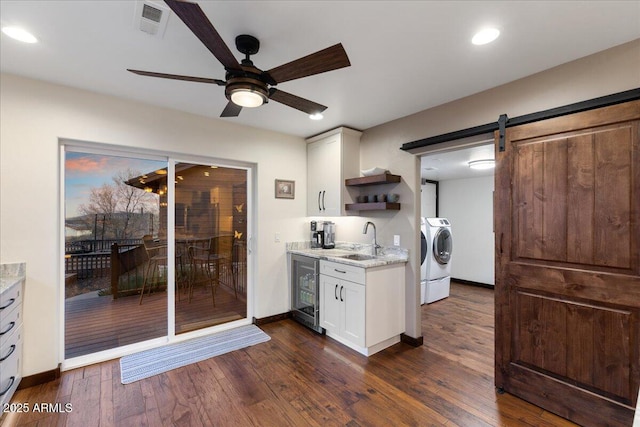 kitchen featuring white cabinetry, sink, a barn door, and washing machine and dryer