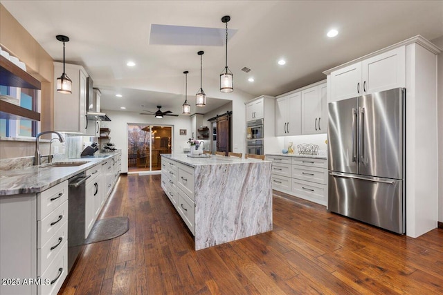 kitchen with a barn door, appliances with stainless steel finishes, a large island, and pendant lighting