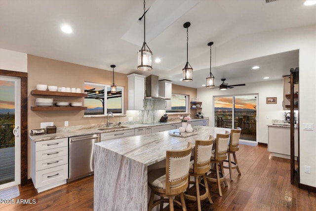 kitchen featuring sink, white cabinetry, a center island, dishwasher, and wall chimney range hood