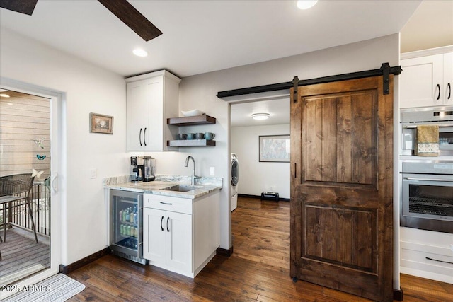 kitchen with sink, beverage cooler, white cabinets, and a barn door