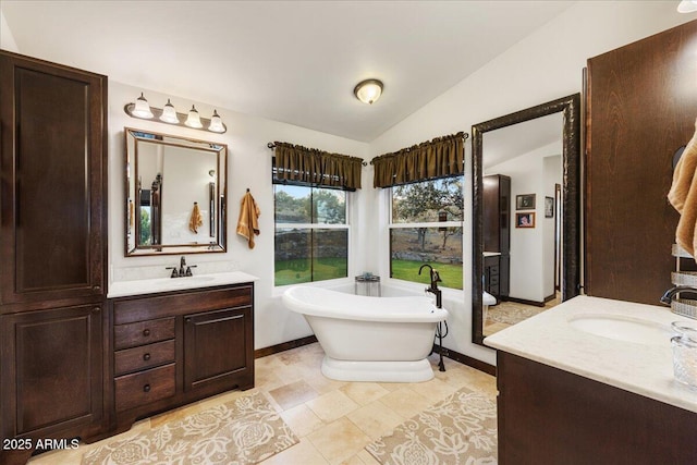 bathroom with vaulted ceiling, vanity, and a bathtub