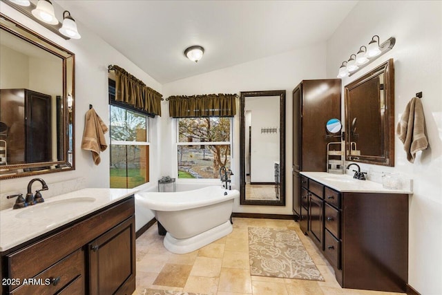 bathroom featuring vaulted ceiling, vanity, and a tub to relax in