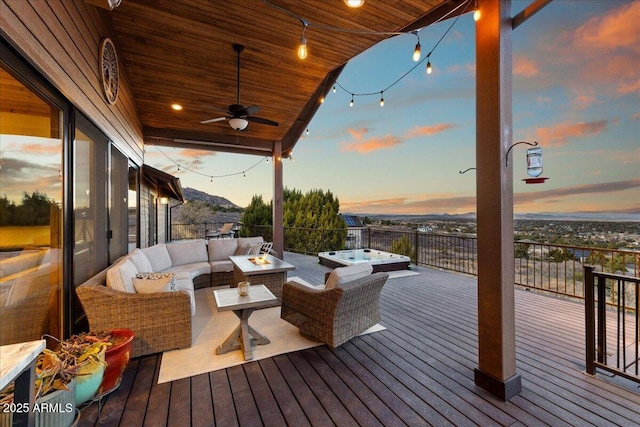 deck at dusk featuring ceiling fan, an outdoor hot tub, and an outdoor living space