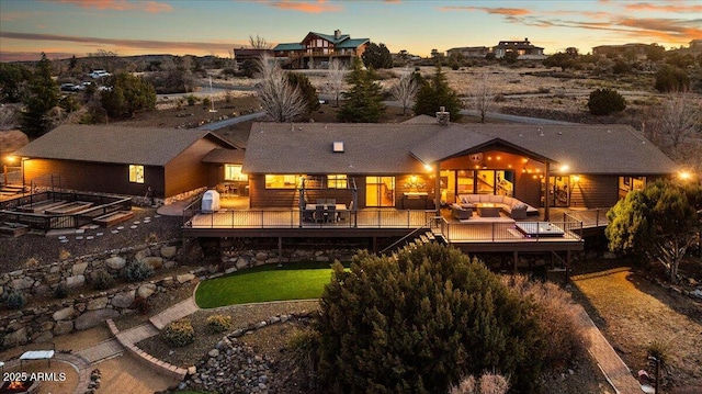 back house at dusk featuring an outdoor living space, a deck, and a patio area