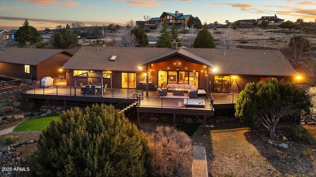 back house at dusk featuring an outdoor hangout area and a deck