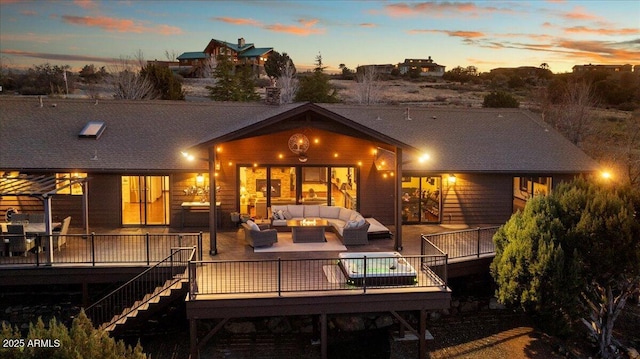 back house at dusk with a wooden deck and an outdoor hangout area