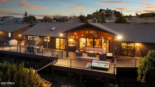 back house at dusk featuring a wooden deck and outdoor lounge area