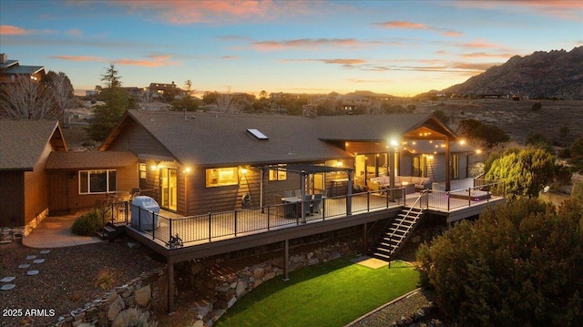 back house at dusk with a wooden deck and a patio area