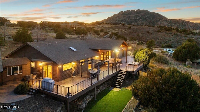 back house at dusk with outdoor lounge area and a deck with mountain view