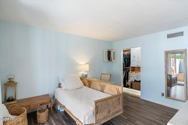 bedroom with a walk in closet, dark hardwood / wood-style floors, and a closet