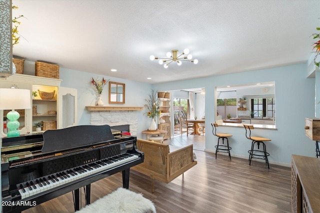 miscellaneous room featuring a textured ceiling, wood-type flooring, a fireplace, and an inviting chandelier