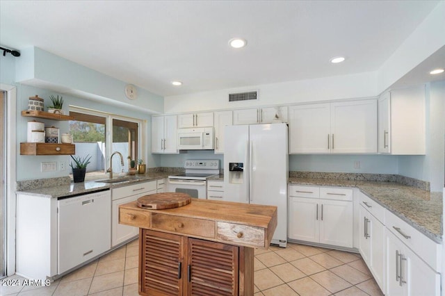 kitchen with white cabinetry, sink, light tile patterned flooring, and white appliances