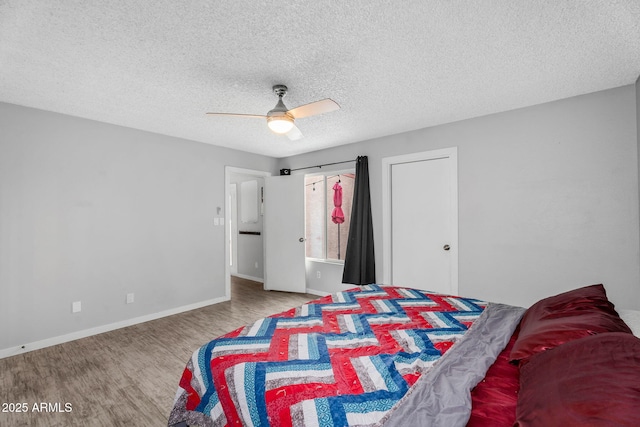 bedroom featuring ceiling fan, baseboards, wood finished floors, and a textured ceiling