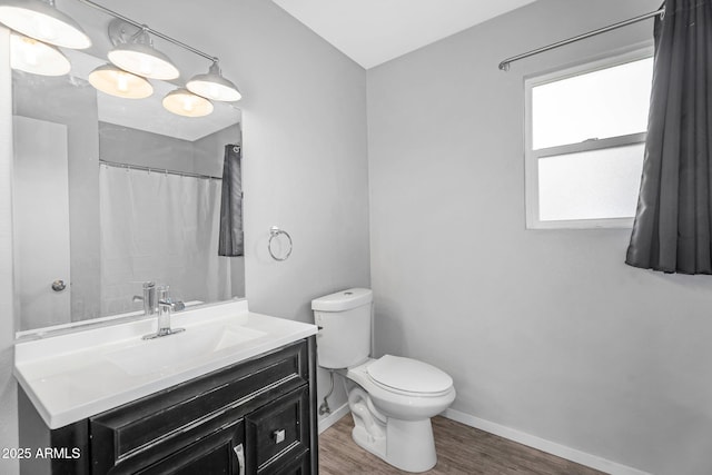 bathroom featuring toilet, baseboards, wood finished floors, curtained shower, and vanity
