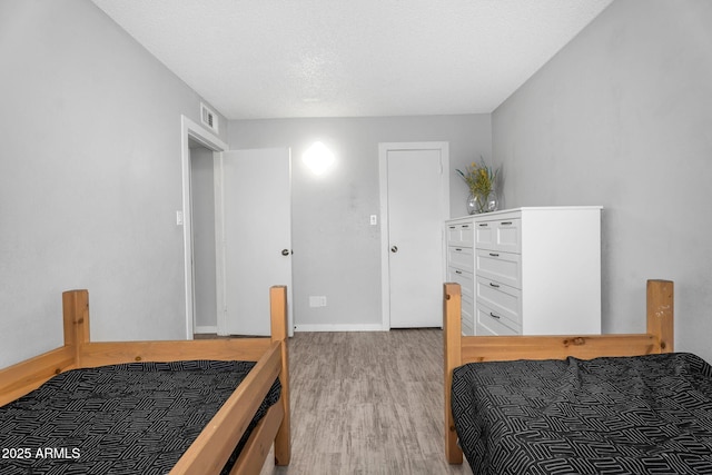 bedroom with wood finished floors, visible vents, and baseboards